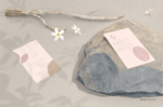 Simple and elegant business card mockup placed on stone with branches and flowers.